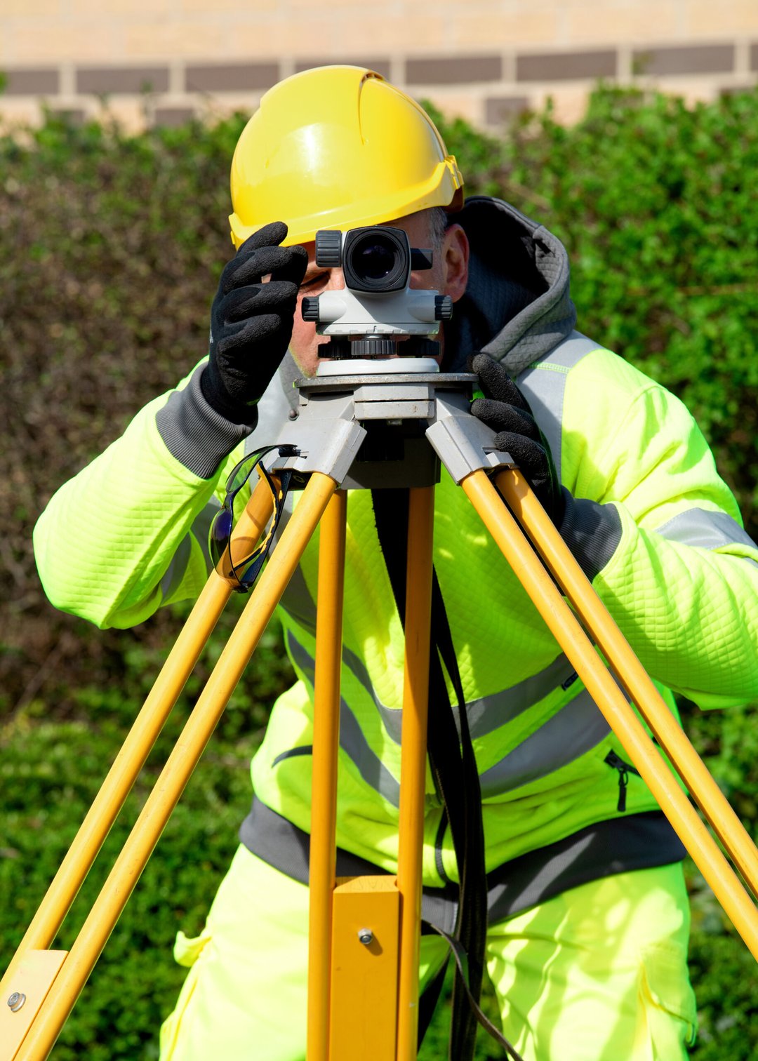 Man surveying a site with a theodolite, looking towards the camera